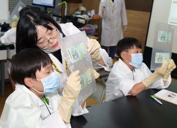 '2019 과학수사 체험캠프' 참가 학생들이 가상의 사건현장에서 발견한 지폐의 위조여부를 자외선을 이용해 감별하는 실험에 열중하고 있다.