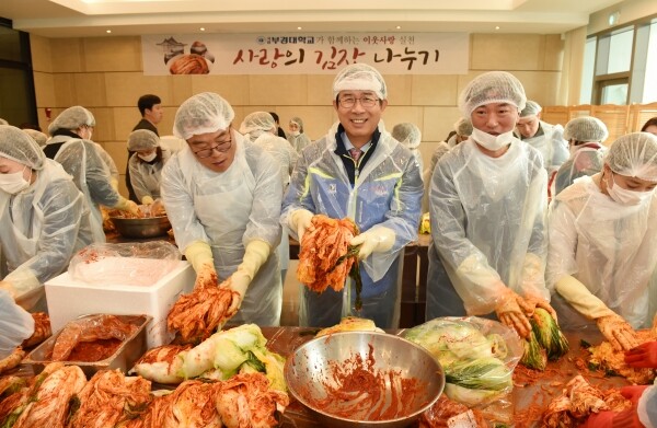 부경대 김영섭 총장(가운데)이 직접 양념을 치댄 배추를 들고 활짝 웃고 있다.
