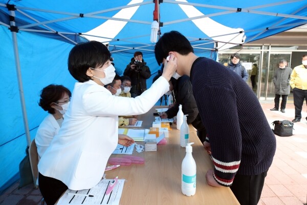 강원대학교 관계자가 2월 21일(금) 오전 외국인 유학생 자율격리 생활관 입구에 설치된 간이 검역시설에서 체온을 측정하는 모습을 시연하고 있다. (사진: 강원대 제공)