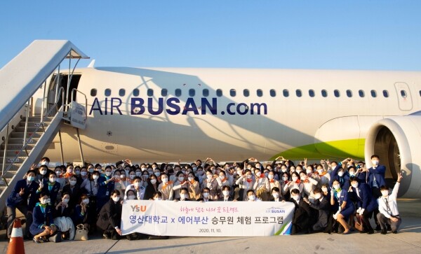 지난 10일 열린 ‘에어부산 캐빈크루 스탠바이’에 참여한 와이즈유(영산대학교) 항공관광학과 학생들이 항공기(BX8910편) 앞에서 기념촬영을 하고 있다. (사진=와이즈유 제공)