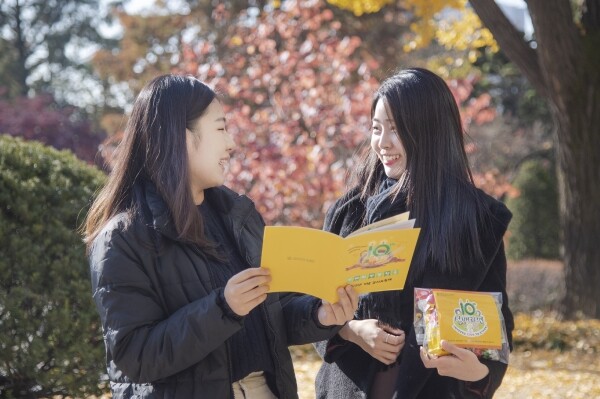 이화여대 재학생들이 선배라면 팸플릿과 라면 기념품을 들고 밝은 표정으로 대화를 나누고 있다. 사진=이화여대