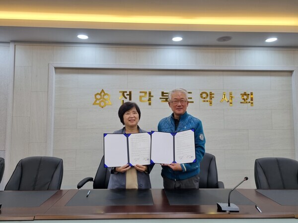 채한정(왼쪽) 전북대 약학대학장과 서용훈 전북약사회장이 전북대 약학대 실무실습교육에 대한 협약을 체결한 뒤 협약서를 펼쳐보이고 있다. 사진=전북대 제공