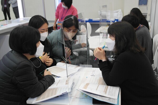 한 대학 관계자가 감염병 예방을 위해 설치한 칸막이를 사이에 두고 수험생들에게 대학 정시 전형 소개와 이를 바탕으로 한 1대 1 맞춤형 상담을 하고 있다. 사진=임지연 기자