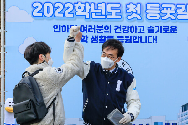 조명우(오른쪽) 인하대 총장과 학생이 인하대 후문에서 열린 ‘첫 등굣길 총장님과 함께하는 학생 환영행사’에서  반갑게 인사하고 있다. 사진=인하대 제공