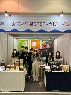 충북대 GTEP사업단 학생들이 2022 제주식품대전 제주잇수다 부스에서 협력업체 제품을 홍보하며 기념촬영하고 있다. 사진=충북대 제공