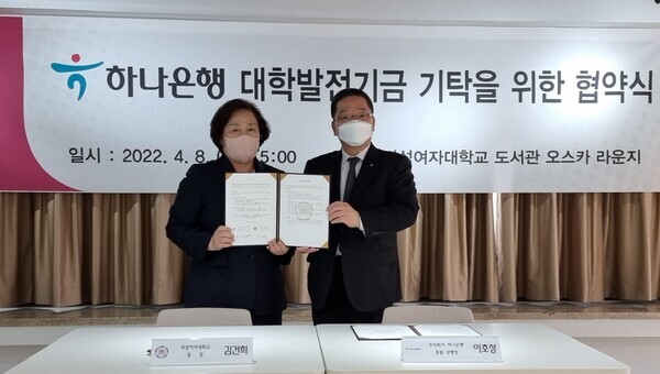 김건희(왼쪽) 덕성여대 총장과 이호성 하나은행 총괄 부행장이 양 기관의 공동발전과 상호협력을 위한 협약을 체결한 후 협약서를 들어보이며 기념촬영하고 있다. 사진=덕성여대 제공
