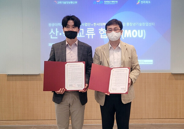 원광대 SW중심대학사업단과 한서대 충남서부권 중장년기술창업센터 관계자들이 산학교류 협약식에서 협약서를 펼쳐보이고 있다. 사진=원광대 제공