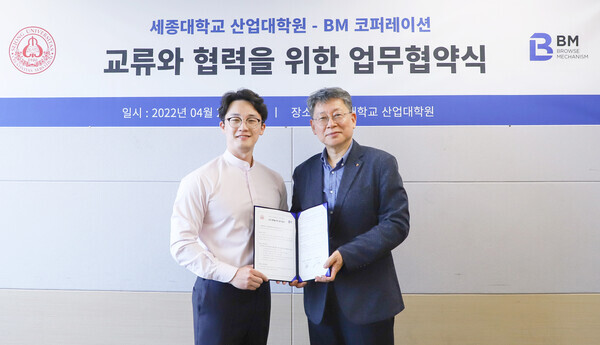 배기형(오른쪽) 세종대 산업대학원장과 박주형 BM코퍼레이션 대표이사가 업무협약을 체결한 뒤 협약서를 펼쳐보이고 있다. 사진=세종대 제공