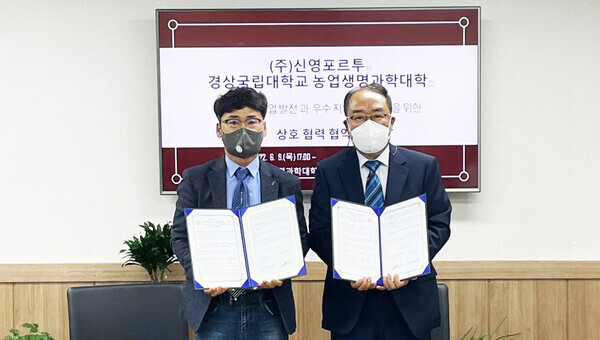 김철환(왼쪽) 경상국립대 농업생명과학대학장과 노재남 신영포르투 사장이 상호협력 협정을 체결한 뒤  협약서를 펼쳐보이고 있다. 사진=경상국립대 제공