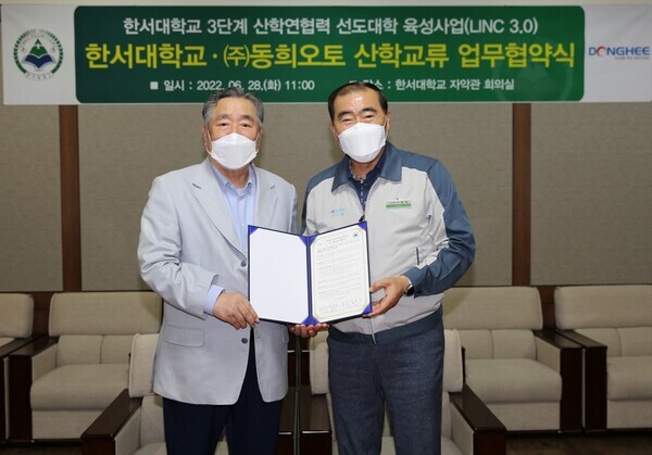 함기선(왼쪽) 한서대 총장과 박광식 동희오토 대표가 업무협약식에서 협약서를 펼쳐보이고 있다. 사진=한서대 제공