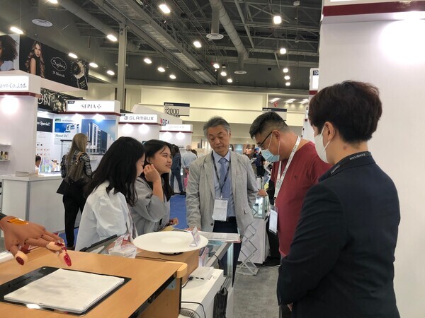 지난 12~14일 미국에서 열린 코스모프로프 라스베가스 전시회에 참가한 전북대 GTEP사업단 소속 박세희·최미소씨가 외국 바이어들에게 제품 설명을 하고 있다. 사진=전북대 제공 