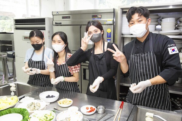 영산대가 지난 12일 유학생들을 대상으로 실시한 ‘환경도시락 만들기 체험’ 행사에서 유학생들이도시락을 만드는 도중 손가락으로 V자를 만들어보이고 있다. 사진=영산대 제공 