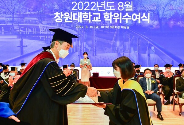 이호영 창원대 총장이 19일 창원대 ‘2022년 8월 학위수여식’에서 졸업생과 악수하며 축하하고 있다. 사진=창원대 제공