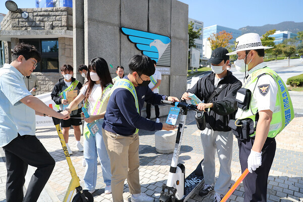 부산대 교직원과 학생들이 30일 대학 정문 앞에서 시민들을 대상으로 ‘개인형 이동장치 교통안전캠페인’을 실시하고 있다. 사진=부산대 제공